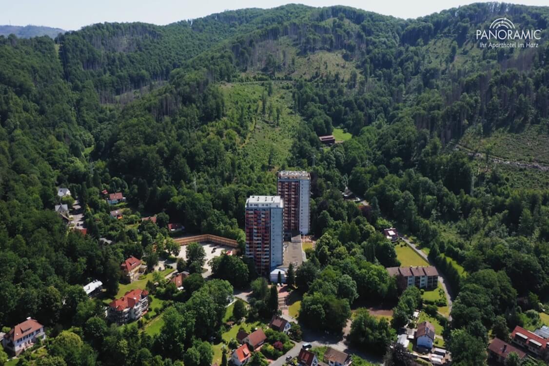 Vogelperspektive auf das Panoramic Hotel im Harz, umgeben von dichtem Wald und grüner Natur.